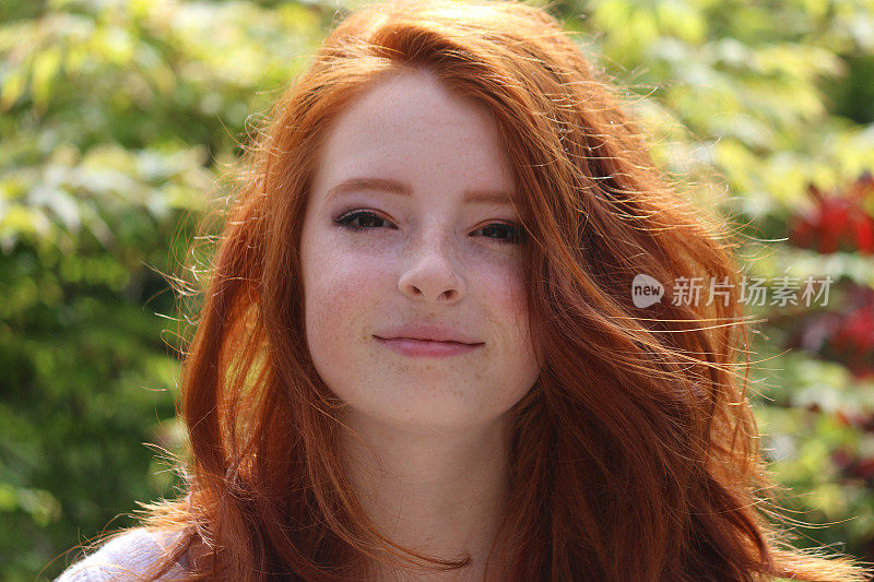 这是一个14 / 15岁的红发少女的形象，她的春季妆容衬托了她苍白的皮肤和雀斑，看着相机，模糊的春叶色彩背景